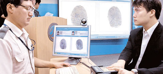 ３０日、法務部の職員が「外国人指紋確認システム」を試演している。