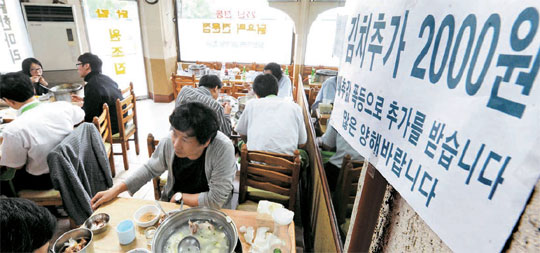 ソウル市内の飲食店が「キムチ追加２０００ウォン」と書かれた紙を貼って営業している。