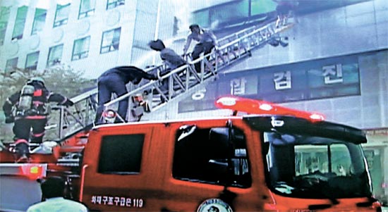 ２２日午後、火事が発生したソウル江南区三成洞５階建てビルの事務室から、職員が消防車のはしごを伝って脱出している。