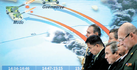 駐韓武官らが２３日、北朝鮮の延坪島砲撃状況を示すグラフィック映像を背景に黙祷している。