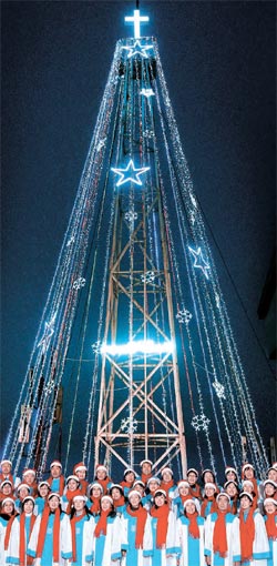 ２１日、愛妓峰展望台で７年ぶりに点灯されたクリスマスツリーの前で汝矣島純福音教会合唱団員が賛美歌を歌っている。