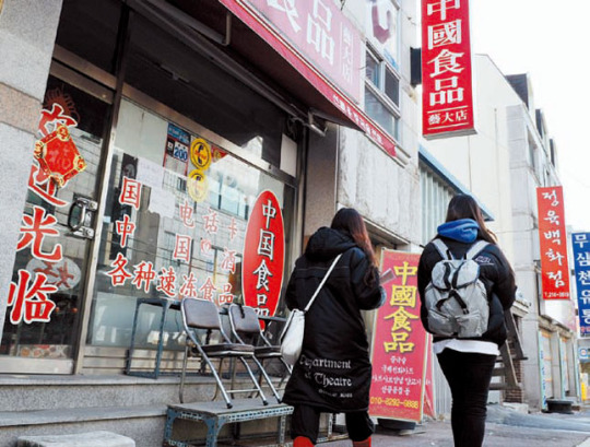 大学近くの中国物産品店の前を通る学生。