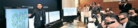 写真＝三星電子映像ディスプレー事業部開発チーム研究員（左側）が８日、ＬＧ電子３Ｄテレビを比較し製品の特徴を説明している。