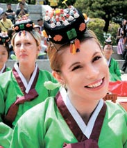 ６日、成年式に参加した外国人女子学生が頭に冠を使って喜んでいる。