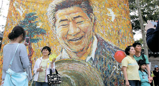 市民が盧武鉉前大統領の絵を背景に記念写真を撮影している。