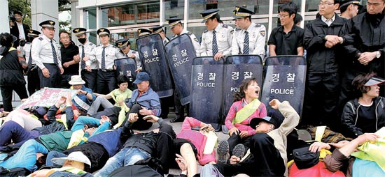 建物への進入を警察に制止された釜山貯蓄銀行被害者が入口で横になりながら抗議している。