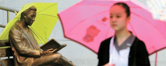 全国的に梅雨が始まった２２日、ソウル・世宗（セジョン）文化会館の前である市民が、誰か傘をかぶせた銅像の前を過ぎている。