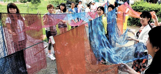 多文化家族移住女性らの天然染色スカーフ作り体験行事が開かれた。染色作業を終えた女性たちがスカーフを物干しに広げている。