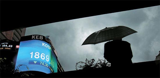 米国発の格付け引き下げのニュースは８日、ソウルの天気のように韓国経済に暗雲を立ちこめさせた。写真はＫＯＳＰＩ指数７４．３０ポイント（３．８２％）の急落を伝える外換銀行本店の電光掲示板前の風景。
