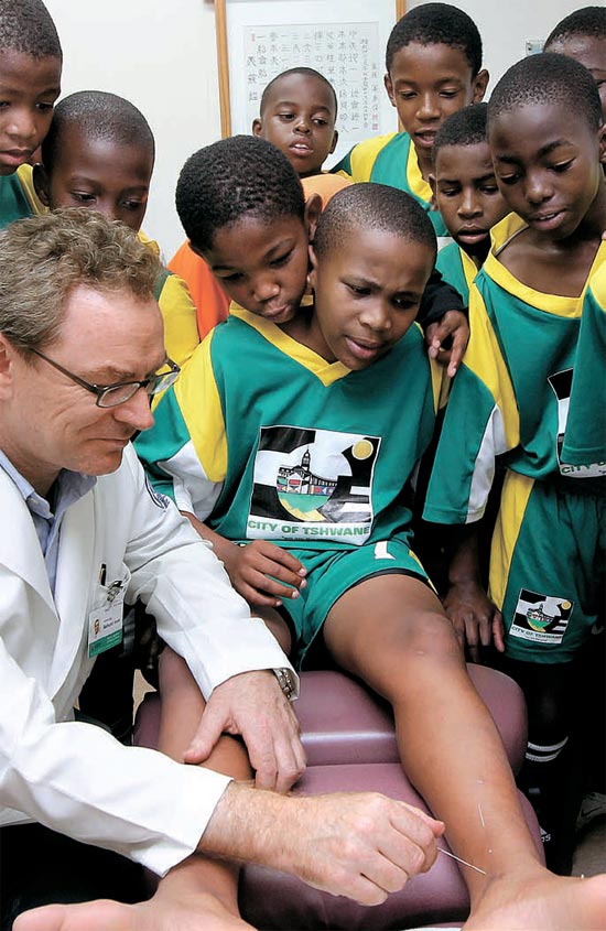 ライムント・ロイアー病院長が足を痛めた子どもにはり治療を施している。