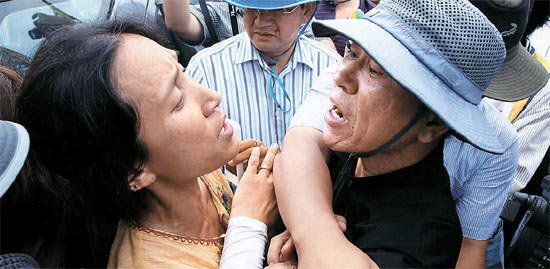 住民の女性（左）が表示板設置作業を撮影した警察官ともみ合っている。