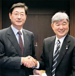 中央メディアネットワークの宋弼鎬副会長（左）と朝日放送の脇阪聰史社長が１０日、大阪のＡＢＣ本社で相互協力覚書に署名後握手している。