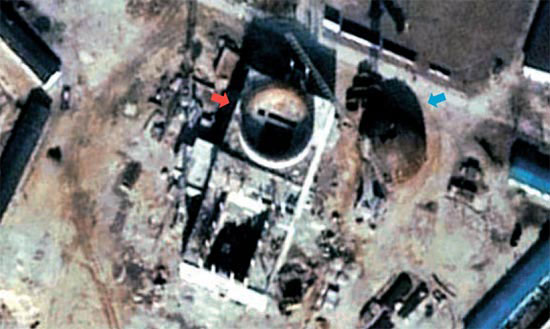長方形の建物が原子力発電所の建物で、すでに外壁がほぼ完成した。上側の丸い部分（赤い矢印）は原子炉が設置される部分で、下の方には原子力発電所設備などが入ることになる。建物右側の丸い構造物（青い矢印）は原子炉の屋根と推定される（写真＝ワシントンポストウェブサイト）。