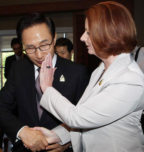オーストラリアのギラード首相が１９日、インドネシア・バリ島の国際コンベンションセンターで、李明博（イ・ミョンバク）大統領と頬を合わせてあいさつした後、李大統領の顔についたリップスティックを拭いている。
