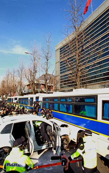 １３日午後、あるデモ隊の１人が、自身の車両を中国大使館を取り囲んでいる警察バスに衝突させた。