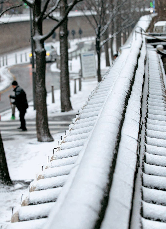 ソウル市庁の職員が徳寿宮（トクスグン）石垣道に積もった雪を除いている。