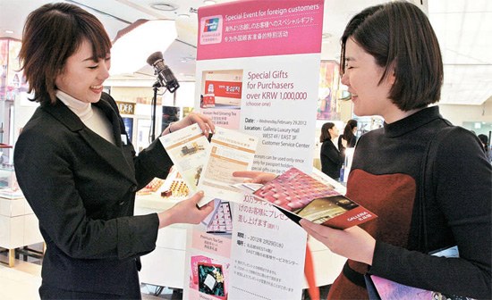 ソウル狎鴎亭洞のギャラリア百貨店で、コンシェルジュ（左）が中国人顧客に景品とショッピング情報を説明している。