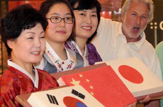 韓国伝統餅専門業者「ジャミ秀」の職員が１３日、ソウル傍花洞（バンファドン）ロッテ百貨店金浦（キンポ）空港店で、韓日中３カ国の国旗をデザインした餅を外国人に見せている。