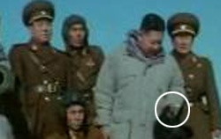 記録映画「白頭の先軍革命偉業を継承せよ」で、金正恩がタンクに上がって軍幹部と写真撮影をする時、左手の指にたばこ（写真の円の中）を挟んでいる