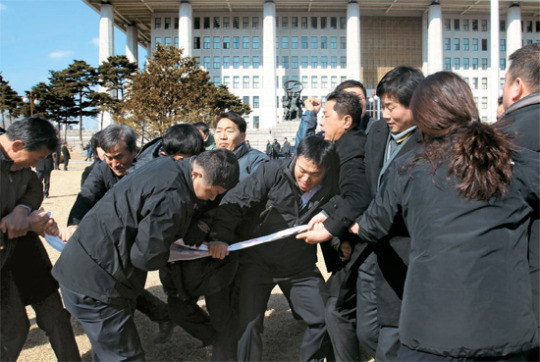 韓国国会の警備員が選挙区統廃合に反対する住民のデモを制止している。