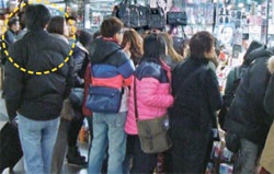 １日、ソウル中区（チュング）南大門地下商店街内にある商店で、日本と中国人観光客たちが買い物をしている。写真左側の黒ジャンパーを着た男性が観光客とともに歩き回る客引きだ。