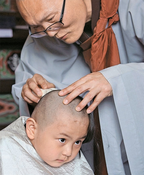 １日、大邱市（テグシ）桐華寺で「童子僧剃髪式および受戒式」が開かれ、僧侶がイ・スンウォン君（６）の髪を剃っている。