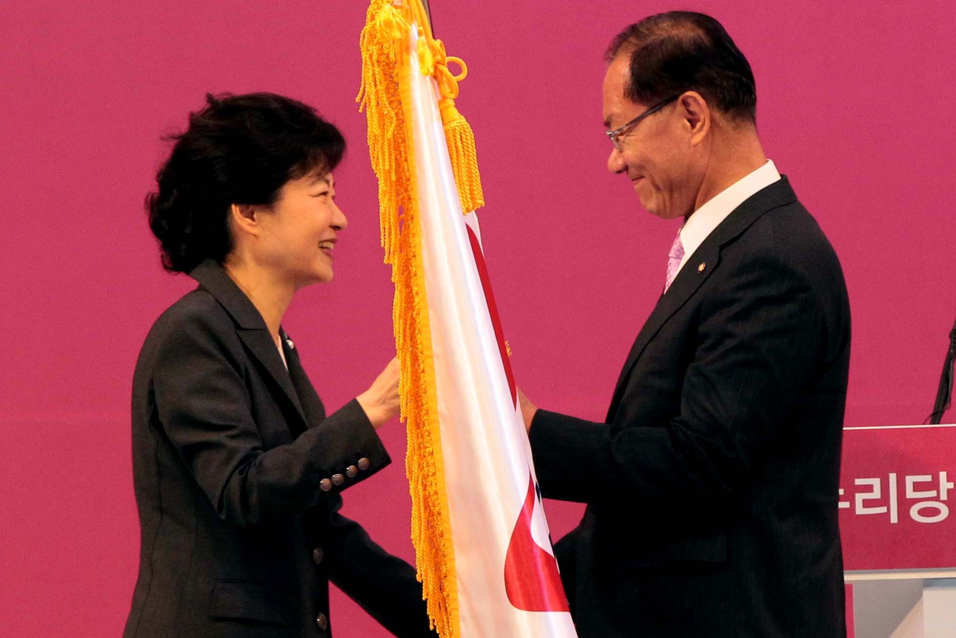 １５日に韓国国際展示場（ＫＩＮＴＥＸ）で開かれたセヌリ党全党大会で代表最高委員に選出された黄祐呂議員が朴槿恵非常対策委員長から党旗を受け取っている。