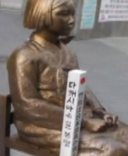 「慰安婦少女像」の隣に「竹島は日本の領土」と書かれた杭が置かれている（写真＝ＪＴＢＣ動画キャプチャー）。