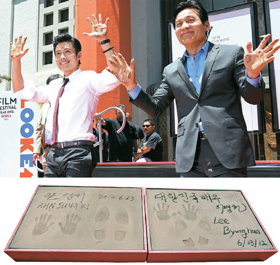 俳優のイ・ビョンホン（写真の左）とアン・ソンギが２３日（現地時間）、米ロサンゼルスのグローマンズ・チャイニーズ・シアターの前で、アジア俳優で初めてハンドプリンティングを行った後、両手を上げてファンの歓呼に応えている。ハンド・フットプリンティング（下の写真）には「大韓民国の俳優イ・ビョンホン、アン・ソンギ」と書かれている。
