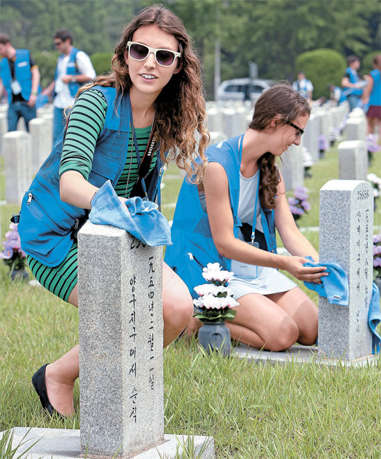 ９日、ソウル国立顕忠院６・２５戦死者墓地を訪れた外国人学生が墓碑を拭いている。