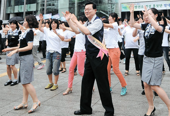 １６日、洪錫禹（ホン・ソクウ）知識経済部長官（前列の真ん中）が、ソウル中央郵便局の前で郵便局の職員と一緒にエネルギーを節約しようという歌に合わせて踊っている（写真＝知識経済部）。