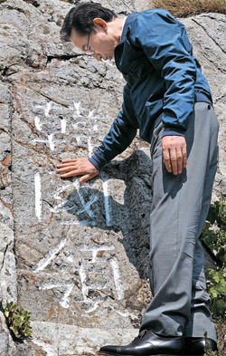李明博（イ・ミョンバク）韓国大統領が１０日午後、独島（ドクト、日本名・竹島）を電撃訪問した。李大統領が１９５４年に独島義勇守備隊が岩に刻んだ「韓国領」という文字を手で触っている。