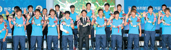 解団式と記者会見を終えた洪明甫（ホン・ミョンボ）監督と選手が花を首にかけ、歓呼するファンに手を振って応えている。