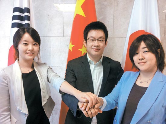 韓日中協力事務局で手を握り合うキム・ヒジンさん、張暮輝さん、松浦昌子さん（左から）。