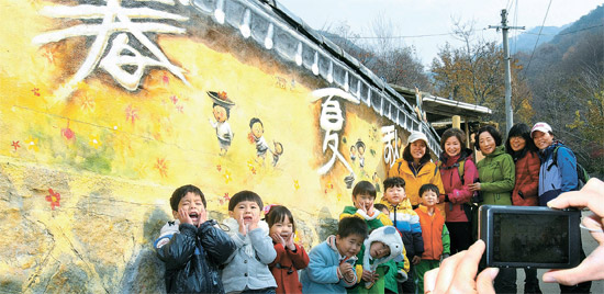 大邱市達城郡（テグシ・タルソングン）の「馬飛亭（マビジョン）壁画村」を訪れた観光客が壁の表面に描かれた絵を背景に写真を取っている。