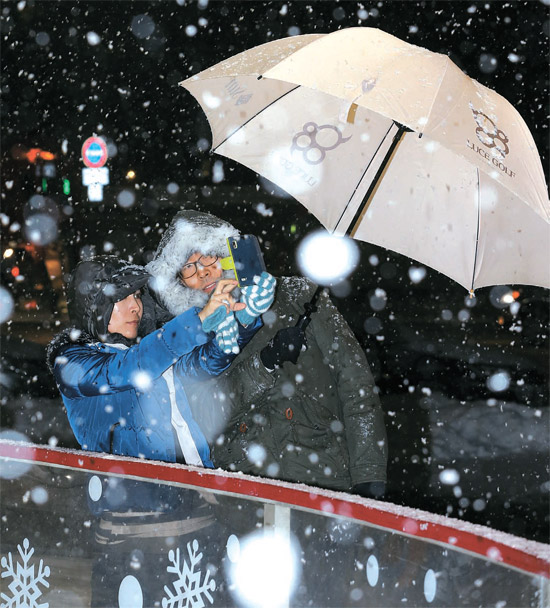 １日夜、ソウル市庁前広場で市民が雪を背景に記念撮影をしている。