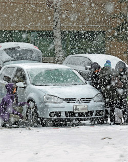 ３日、スペシャルオリンピックが開催されている江原道平昌の竜坪ドーム前で、雪が降る中、市民がタイヤにチェーンを設置している。