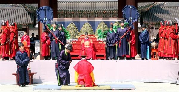 任命された守門将が王の前でひざをついて守門将牌を受けている。
