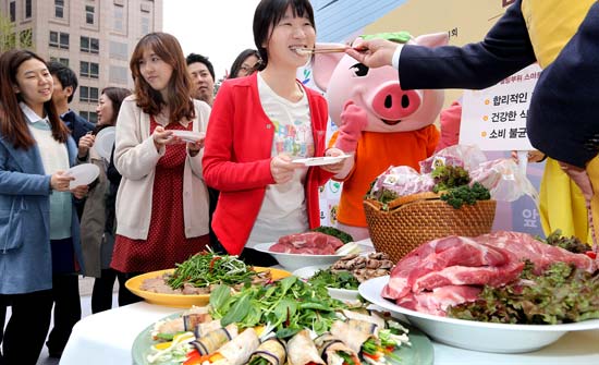 市民が赤身の部分で作った豚肉料理を試食している。