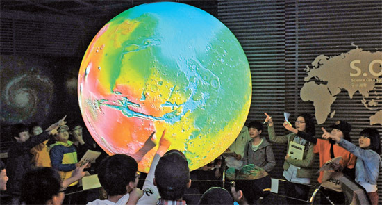 大田市（テジョンシ）の地質博物館で学生が気候変化をひと目で見ることのできる地球の模型を見学している。