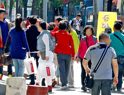 「観光ガイドなのかショッピングガイドなのか…」１６日、ソウル・麻浦区のケンポナシ売り場でショッピングを終えて出てくる外国人団体観光客。手には９６万ウォン分の商品を提げていた。