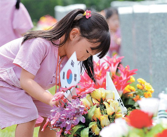 ５日午後、国立大田（テジョン）顕忠院を訪れたある幼稚園児が直接描いた太極旗を墓碑の前にさしている。
