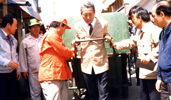 １９９０年４月１０日、ソウル奉天洞で、高建ソウル市長（真ん中）がゴミ回収用リヤカーを引いている。（写真＝高建元首相）