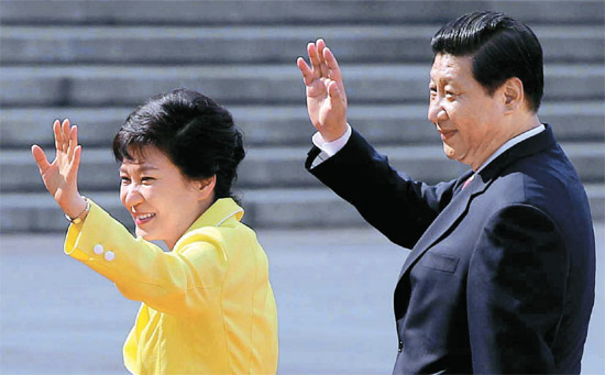 ２７日午後、北京人民大会堂の前で儀仗隊を査閲した後、歓迎客らに手をあげて挨拶している朴槿恵（パク・クネ）大統領（左）と習近平国家主席。
