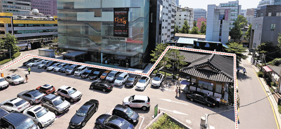 ソウル仁寺洞（インサドン）伝統文化複合施設の予定敷地である公営駐車場の全景（点線内）。瓦ぶきの韓国式家屋が２００６年に開館した仁寺洞広報館だ。その横に駐車場進入路が見える。