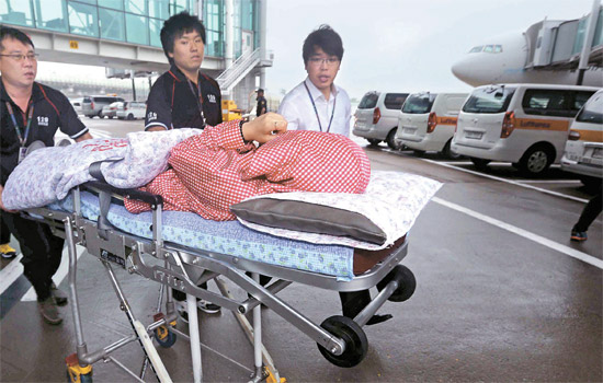 墜落事故航空機の搭乗客のうち１１人が８日午後、仁川（インチョン）国際空港に到着した。搭乗客の１人が移動ベッドに載せられ、病院に運ばれている。