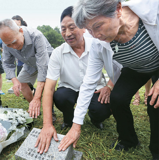 ９日、京畿道坡州積城面（キョンギド・パジュ・チョクソンミョン）の中国軍墓地で、韓国戦争に参戦した中国軍にいた３人が墓碑を触っている。