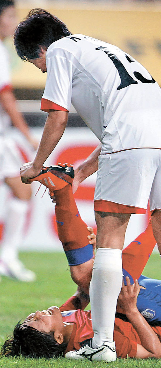北朝鮮のキム・ナムヒ選手がけいれんを起こした韓国の池笑然（チ・ソヨン）選手の筋肉をほぐしている。