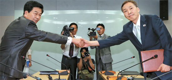 １４日に開城工業団地総合支援センターで韓国側代表のキム・ギウン統一部南北協力地区支援団長（右）と北朝鮮側代表のパク・チョルス中央特区開発指導総局副総局長（左）が合意文を交換した後に握手している。（写真共同取材団）