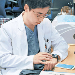 イム・ウヒョンさん（３３）がギャラクシーノート３に保存した診療スケジュールをギャラクシーギアで確認している。